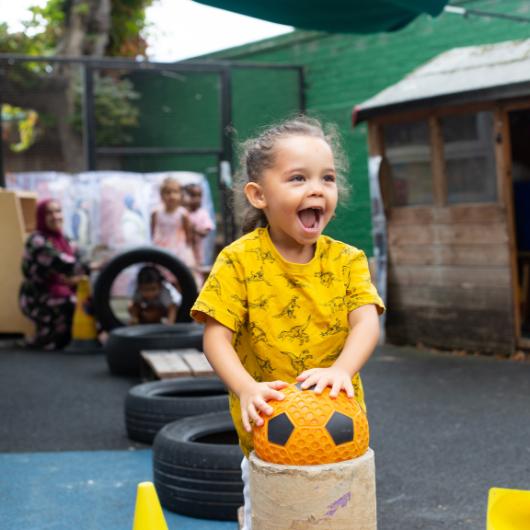 Child playing in playground with ball