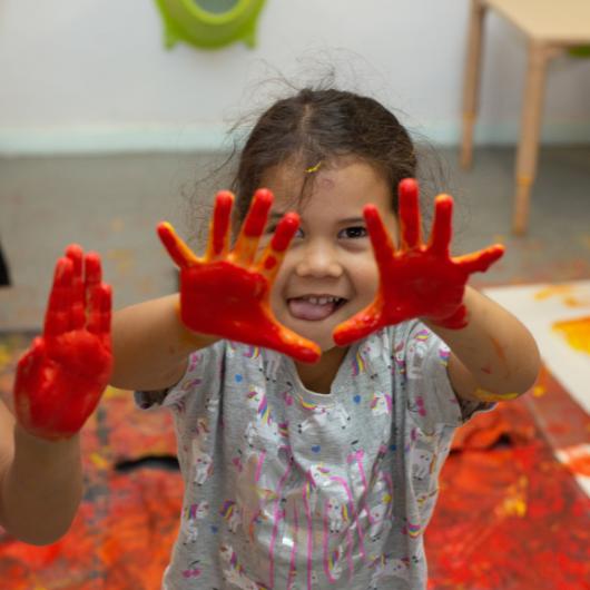 Child showing hands covered in paint