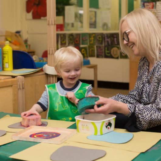 Child doing sponge painting with teacher