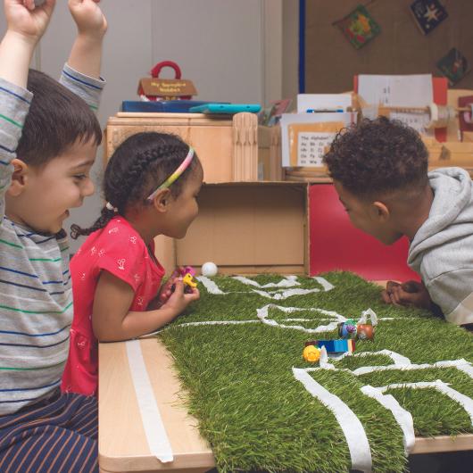 Children playing football with small people