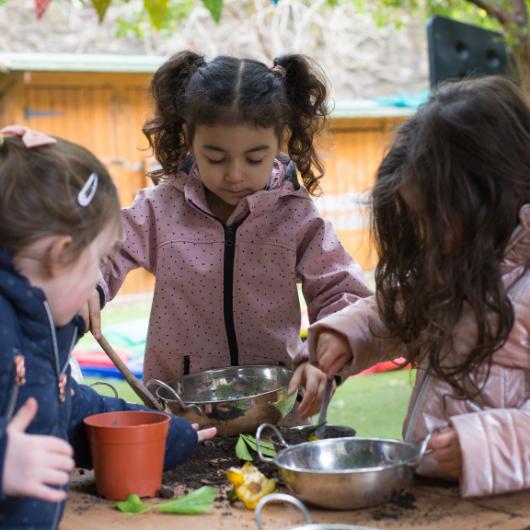 Children playing with bowls and mud outdoors