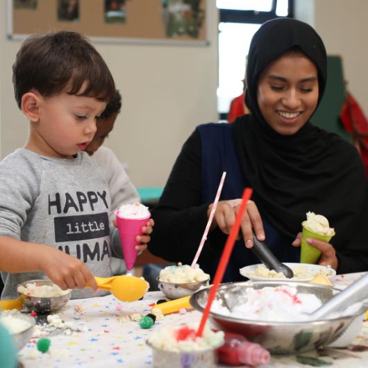 Staff making ice cream cones with child