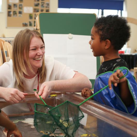 Children and staff member playing with fishing nets