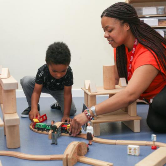 Staff member and child playing with train set