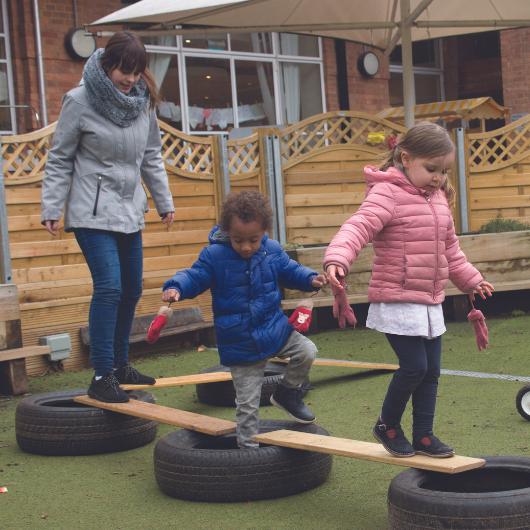 Children doing obstacle course with staff member