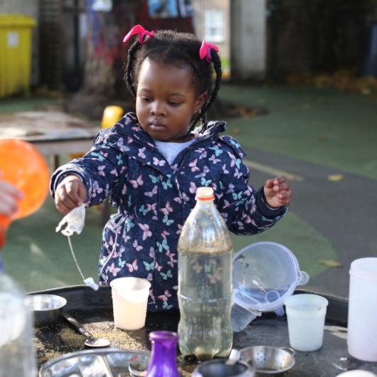 Child playing outside with bottles