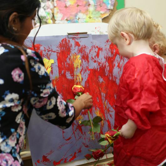 Child using roses to paint with teacher