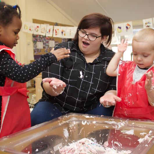 Staff member and children engaging in messy play provocation