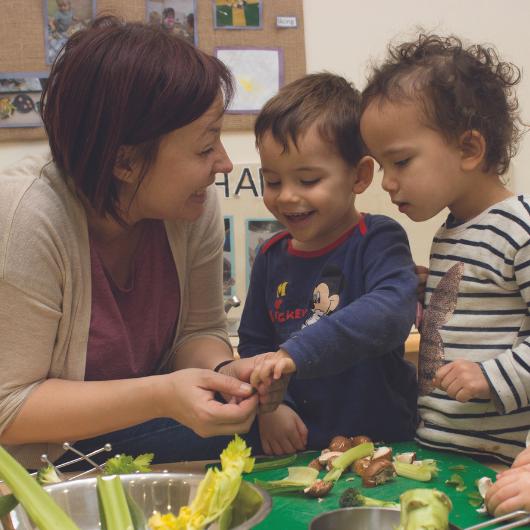 Nursery teacher preparing vegetables with children