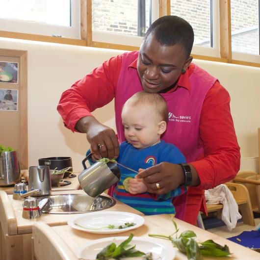 Staff member with baby playing with plants