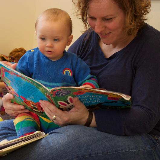 Nursery teacher reading a book with a baby