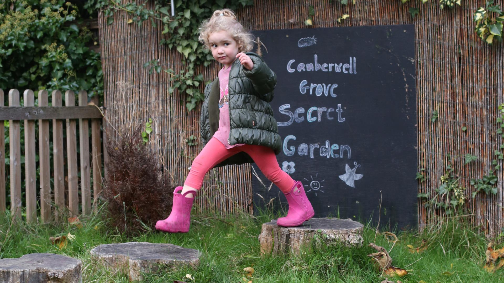 Girl walking across logs in the nursery garden