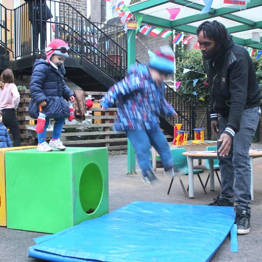 Child jumping off block outdoors on obstacle course