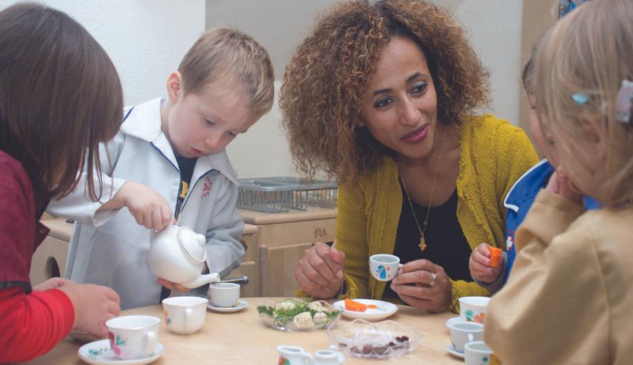 Staff member and children having a tea party