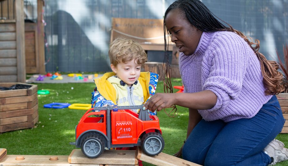 Staff member and child playing with a toy fire engine