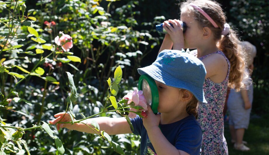 Child looking at the flowers with a magnifying glass