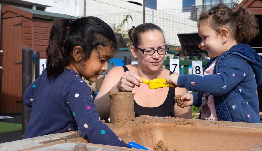 Staff and children playing in the outside sandpit