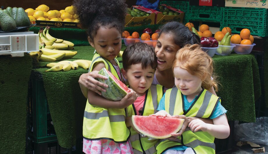 Children and staff holding a watermelon on a trip to a local market