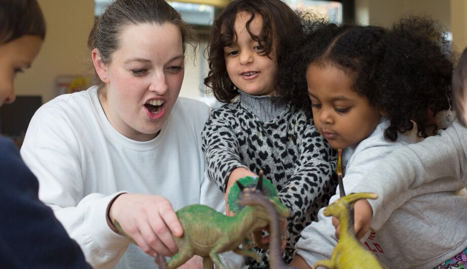 Children and teacher playing with dinosaurs and roaring