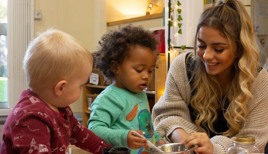 Children transferring dried pasta from a bowl into a cup.