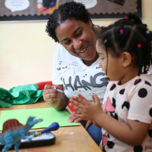 Nursery teacher doing art work with child