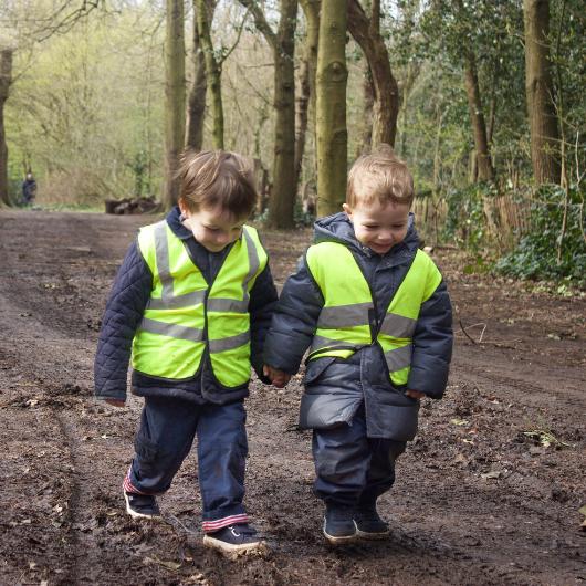 Two children holding hands walking in the local park, exploring