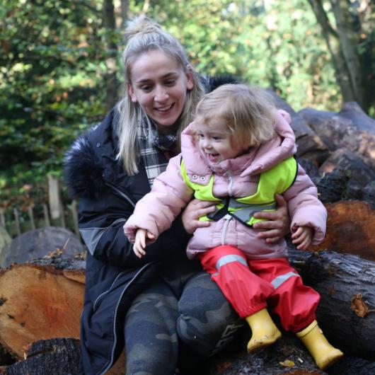 Staff member outside with child sitting on her lap