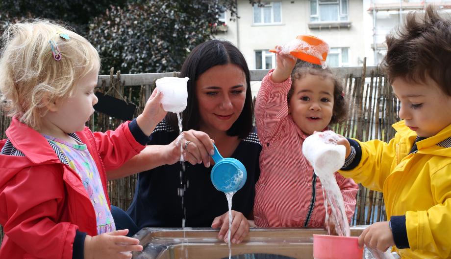 Staff and children playing with water and cups