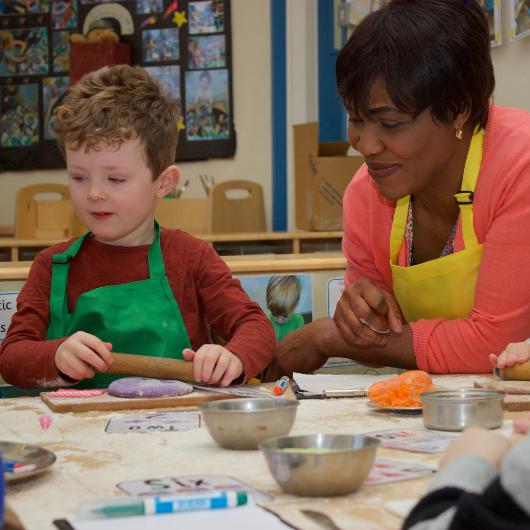 Staff and children doing cooking activity with rolling pins