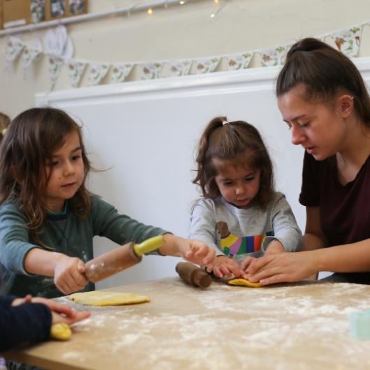 Staff and children rolling dough with rolling pins