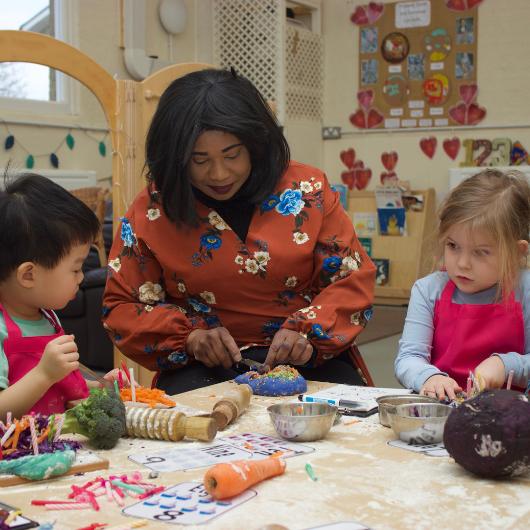 Staff and children making fun vegetable birthday cake