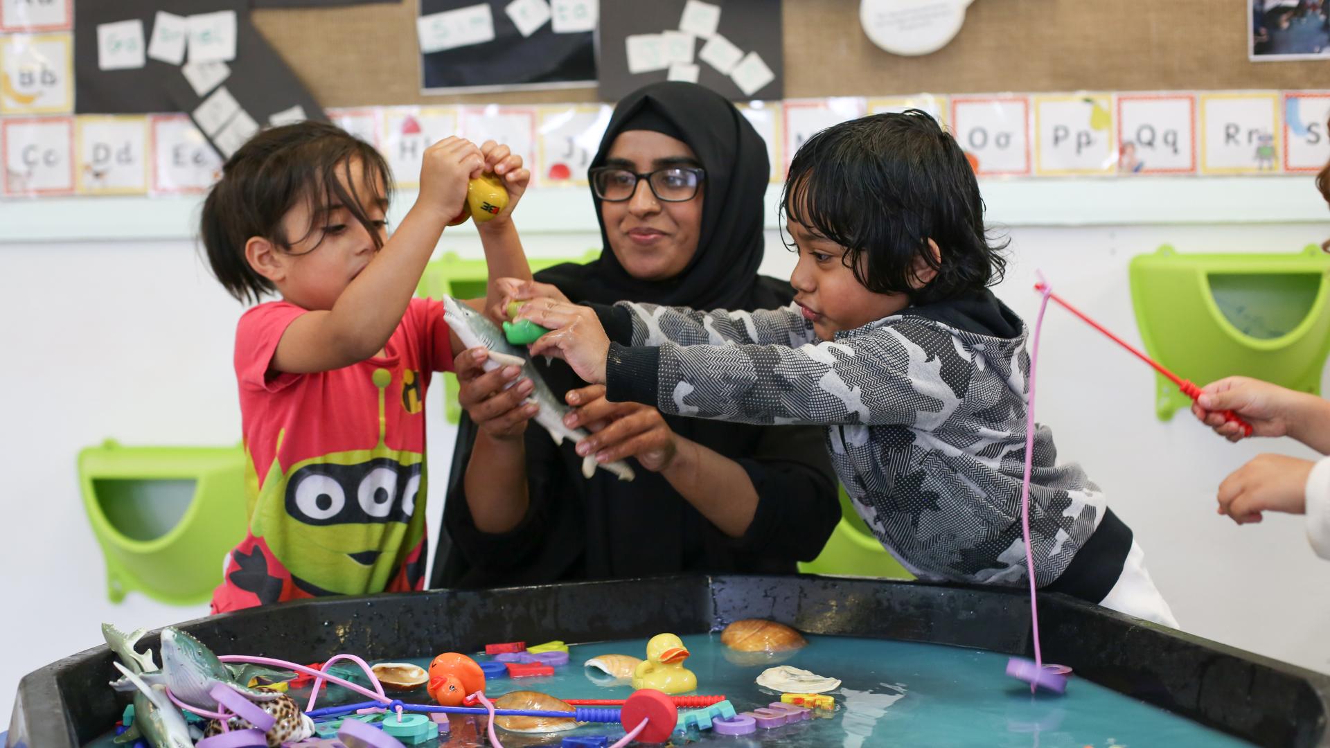 Staff and children playing with water using different animals and fish rods