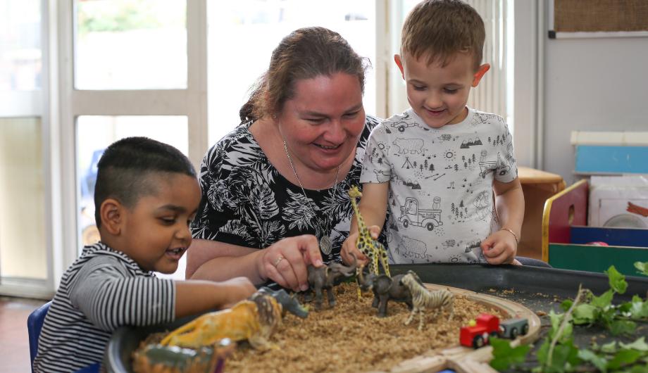 Staff and children playing with natural resources such as weetabix, plants etc to play with plastic animals