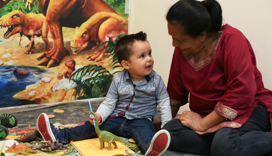 Child playing with dinosaur with teacher