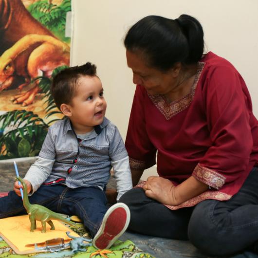 Child playing with dinosaur with teacher