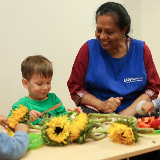 Nursery teacher arranging sunflowers with child