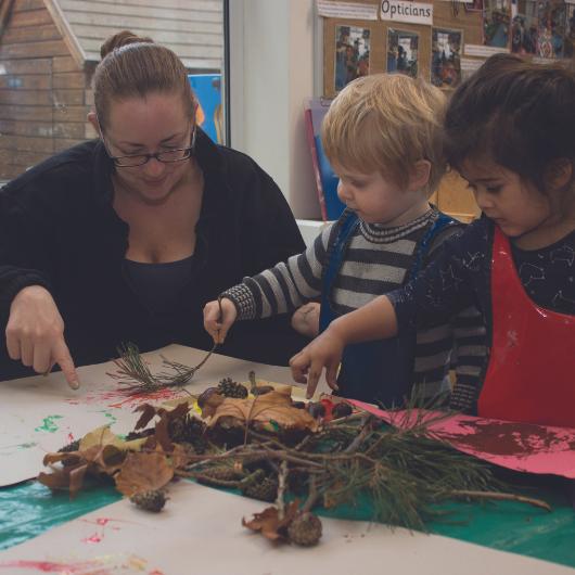 Staff and children doing activity with leaves