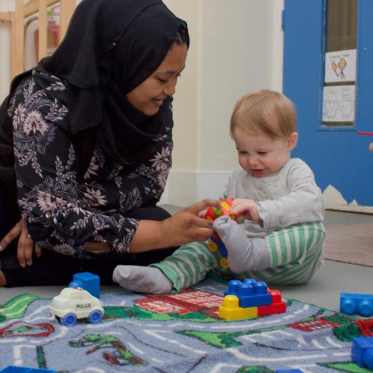 Staff member and baby playing with toy bricks