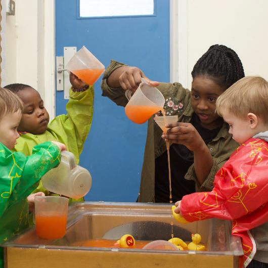 Staff and children doing science experiment with water