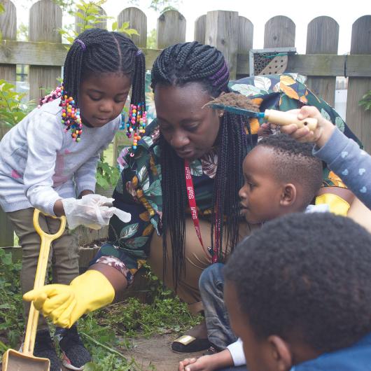 Children and staff digging in the nursery garden