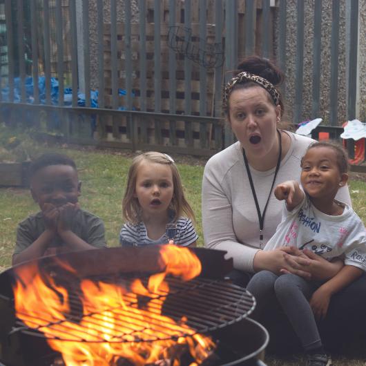 Children and teacher looking from afar at barbeque fire