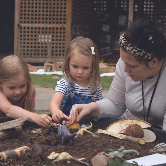 Staff and children playing outside with mud provocation