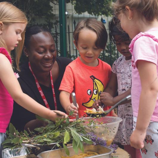 Children making potions in garden with plants in a bowl