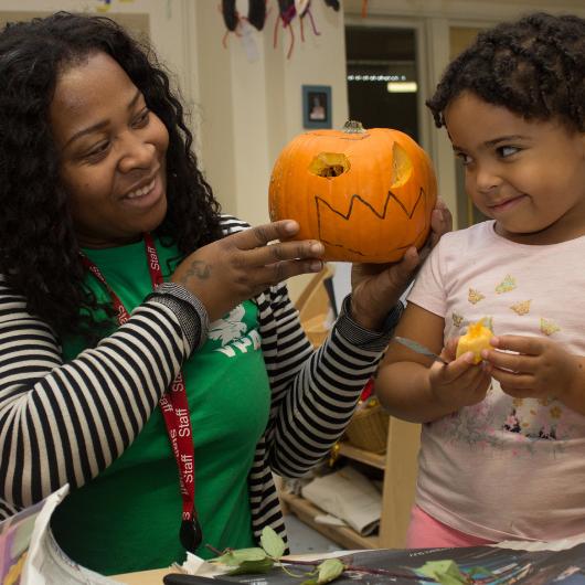 Teacher and children looking at carved pumpkin