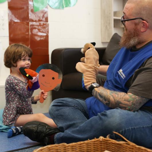 Nursery teacher and child play with puppets