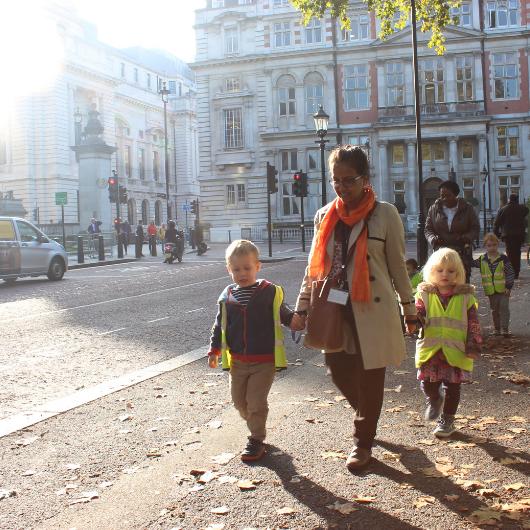 Children out and about crossing the road holding the teacher's hands