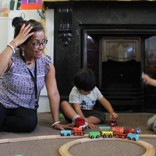 Staff and child play with train set