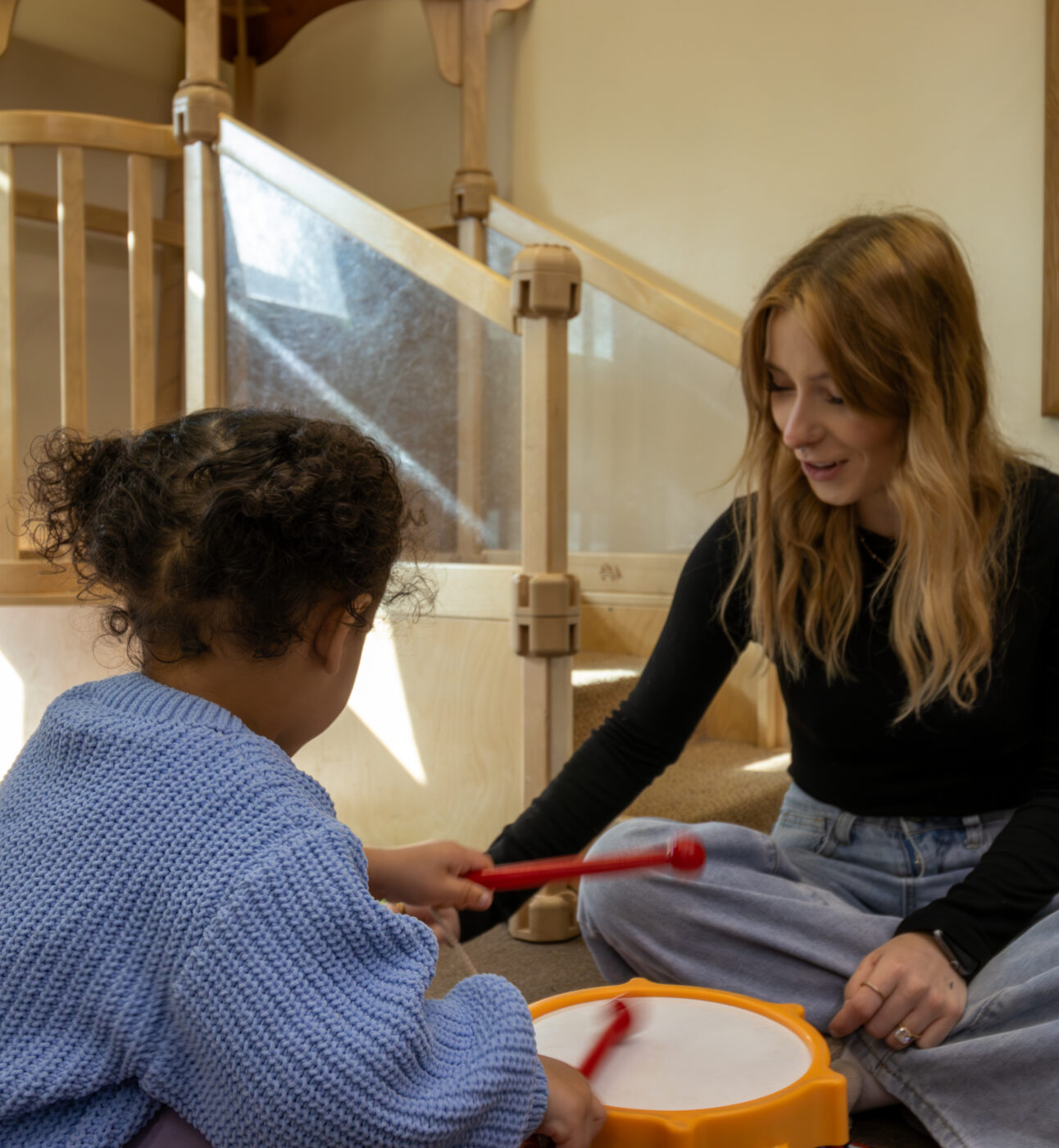 Child playing the drum with teacher