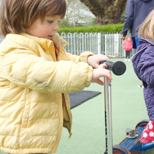 Children ride scooters in the nursery garden