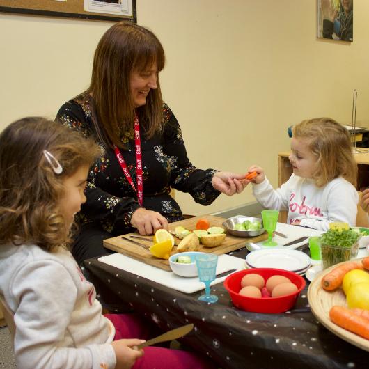 Children tasting fruits and vegetables with nursery teacher